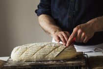 Пекарь нарезает свежеиспеченный хлеб — стоковое фото