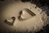 Heart shaped biscuit cutters on dough — Stock Photo