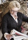 Donna in seggiolone leggendo giornale — Foto stock