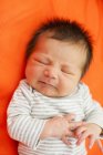 Bebê deitado no travesseiro laranja — Fotografia de Stock