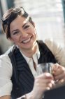 Woman holding glass and smiling at camera — Stock Photo