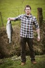 Homme tenant un poisson saumon . — Photo de stock