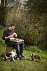 Chef sitting outdoors with dogs — Stock Photo