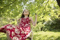 Girl on swing suspending from branches of tree — Stock Photo