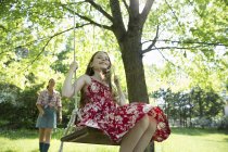 Chica en swing colgando de rama de árbol - foto de stock