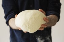 Baker holding a bread dough. — Stock Photo