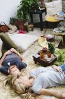 Mulheres deitadas no chão com almofadas e bens pessoais — Fotografia de Stock