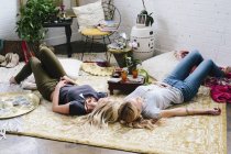 Mulheres deitadas no chão com almofadas e bens pessoais — Fotografia de Stock