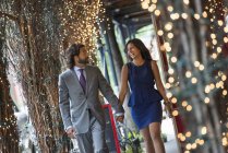 Couple walking under a pergola with lights. — Stock Photo