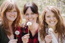 Mulheres segurando dentes-de-leão — Fotografia de Stock