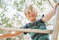 Мальчик на скалодроме в саду — стоковое фото