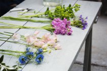 Flores frescas colocadas en el banco de trabajo de una floristería - foto de stock