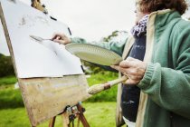 Woman artist working at easel outdoors — Stock Photo
