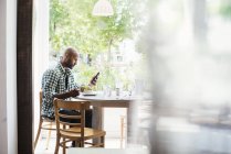 Чоловік сидить у кафе і використовує телефон — стокове фото