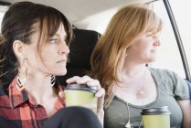 Women in a car with coffee cups. — Stock Photo