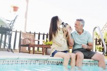 Пара с собакой у бассейна — стоковое фото