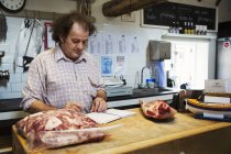 Butcher standing at counter of shop — Stock Photo