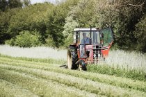 Tractor cutting a swathe in a field. — Stock Photo