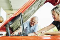 Mujer y hombre mayor reparando un coche - foto de stock