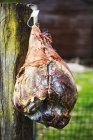 Cured ham hanging on wooden fence — Stock Photo