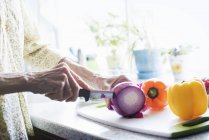 Mulher cortando uma cebola vermelha — Fotografia de Stock