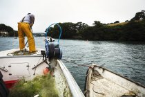 Pescatore in trampolieri su una barca — Foto stock