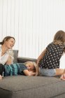 Mère avec des enfants s'amusant sur le canapé — Photo de stock