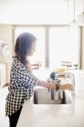 Femme debout à un évier de cuisine . — Photo de stock