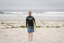 Хлопчик стоїть на піщаному пляжі — стокове фото