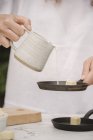 Женщина добавляет молоко в сковороду для омлета . — стоковое фото