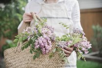 Mujer con cesta de flores rosadas . - foto de stock