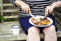 Woman eating from plate on bench — Stock Photo