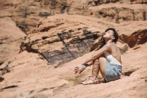 Junge Frau sitzt auf einem Felsen in einer Schlucht. — Stockfoto