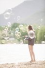Девочка-подросток в окружении мыльных пузырей — стоковое фото