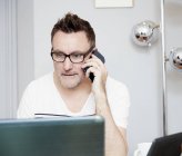 Homme assis au bureau et parlant au téléphone — Photo de stock