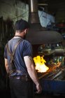 Blacksmith in front of a furnace in a workshop. — Stock Photo