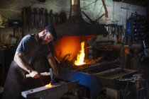 Blacksmith strikes a length of hot metal — Stock Photo