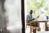 Hombre sentado en la cafetería y usando el teléfono - foto de stock