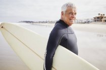 Старший чоловік, що носить дошку для серфінгу . — стокове фото