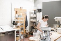 Mujer de pie en el mostrador de trabajo en la panadería - foto de stock