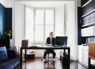 Geschäftsmann sitzt am Schreibtisch im Erker — Stockfoto