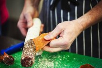 Butcher taking skin off salami — Stock Photo