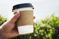 Человеческая рука с одноразовой бумажной чашкой — стоковое фото