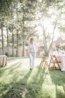 Donna in piedi in un giardino illuminato dal sole — Foto stock