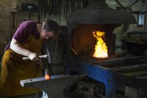 Blacksmith strikes a length of hot metal — Stock Photo