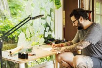 Man with tattoos drawing — Stock Photo