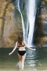 Woman in a black bikini at waterfall — Stock Photo