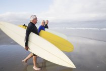 Senior woman and men carrying surfboards. — Stock Photo