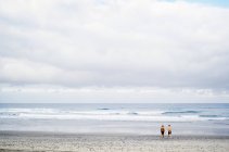 Hombres de pie en una playa de arena - foto de stock