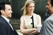 Geschäftsfrau und zwei Geschäftsleute plaudern und lächeln — Stockfoto